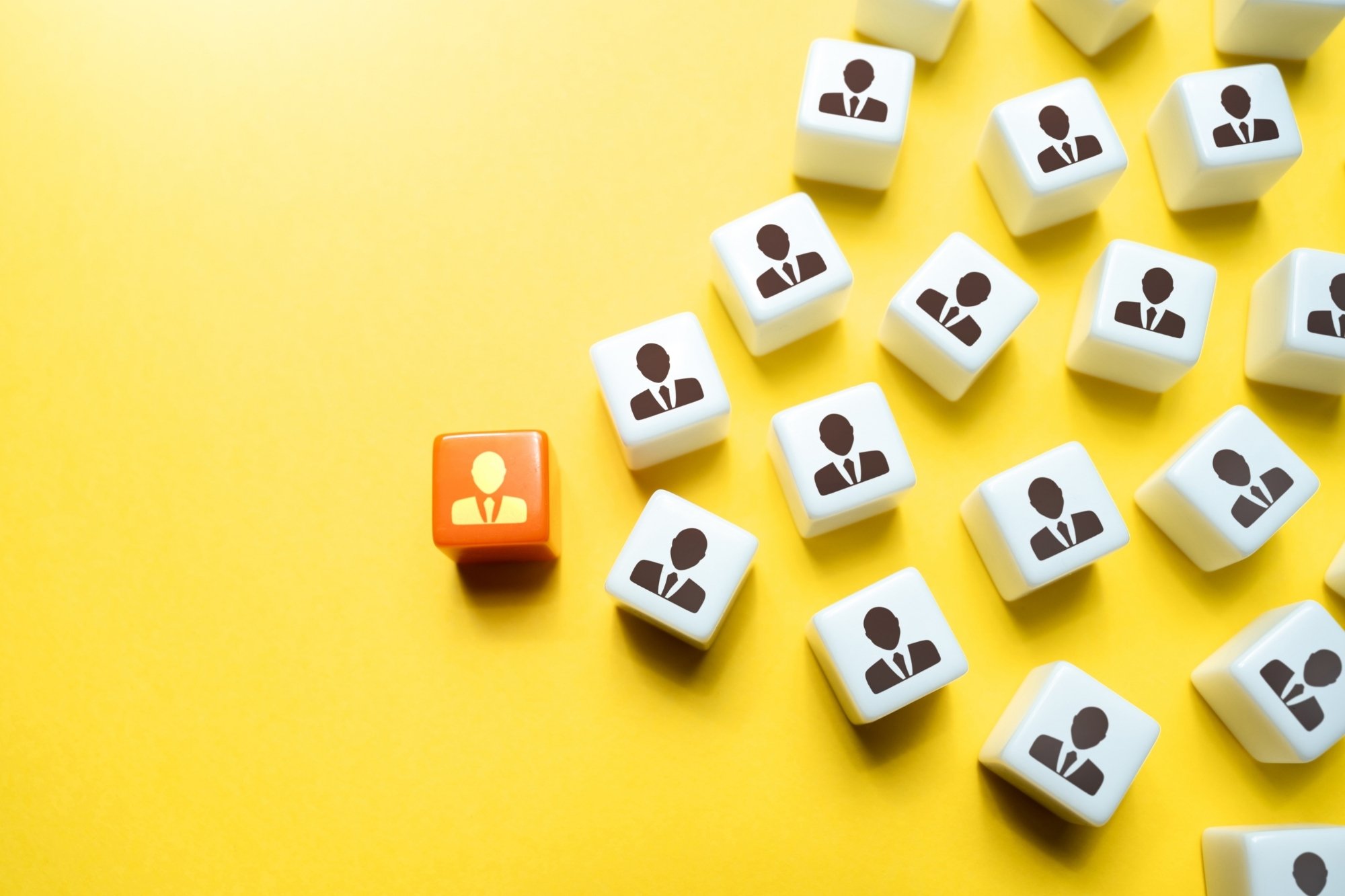 bunch of white dices moving towards one orange dice
