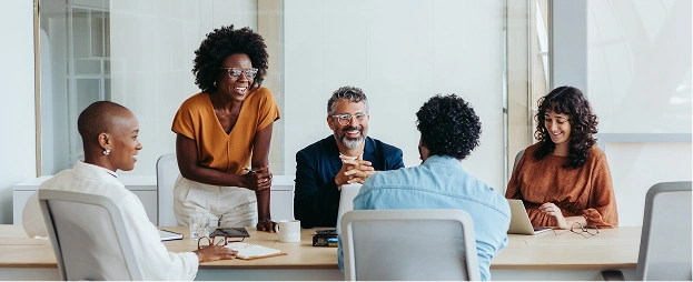 A group of five people sit together in a bright meeting room