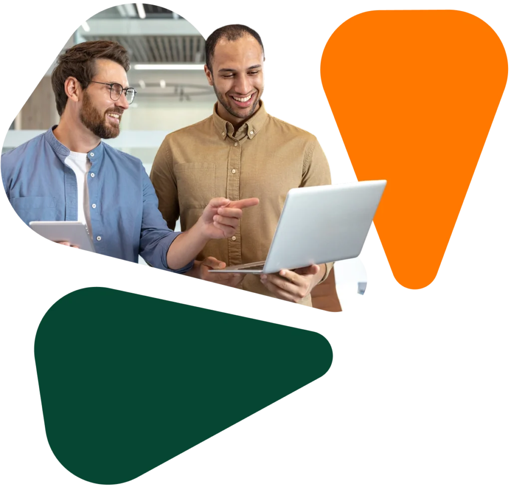 Two cheerful colleagues collaborate on a laptop, discussing ideas with the help of a tablet in a modern office setting