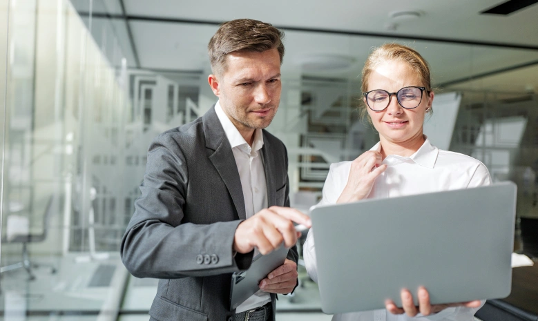 Two professionals reviewing a laptop together in an office