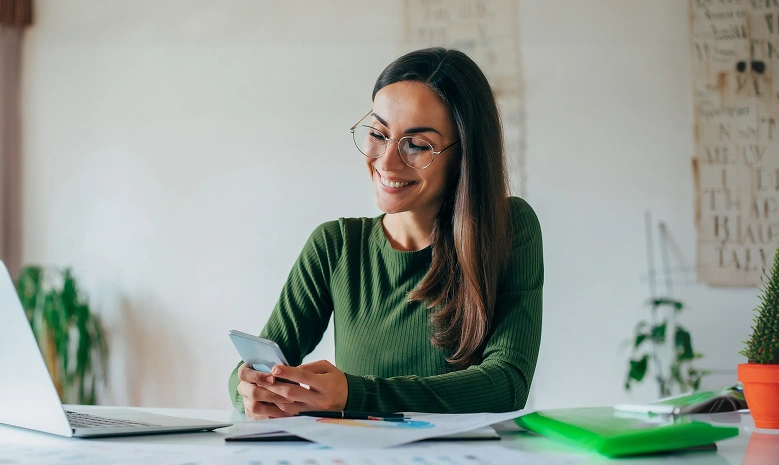 Woman using a smartphone while working at a desk