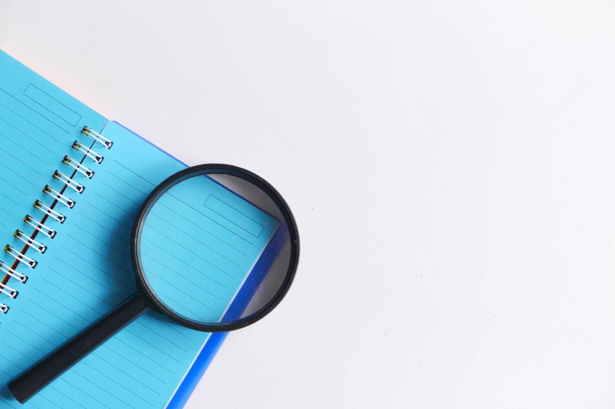 magnifying glass on top of blue notebook