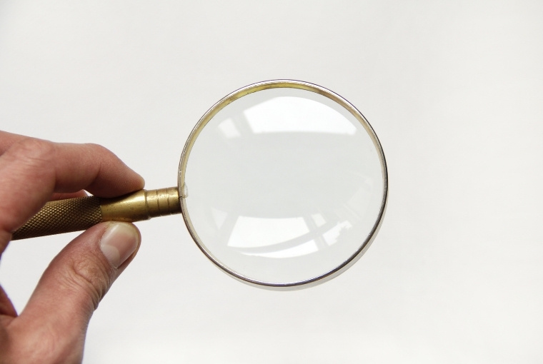 gold magnifying glass in beige background