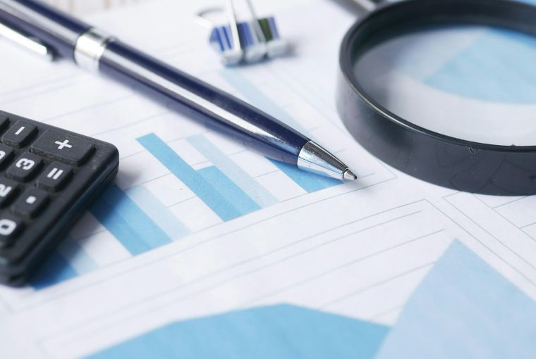 ball pen magnifying glass and calculator on top of charts