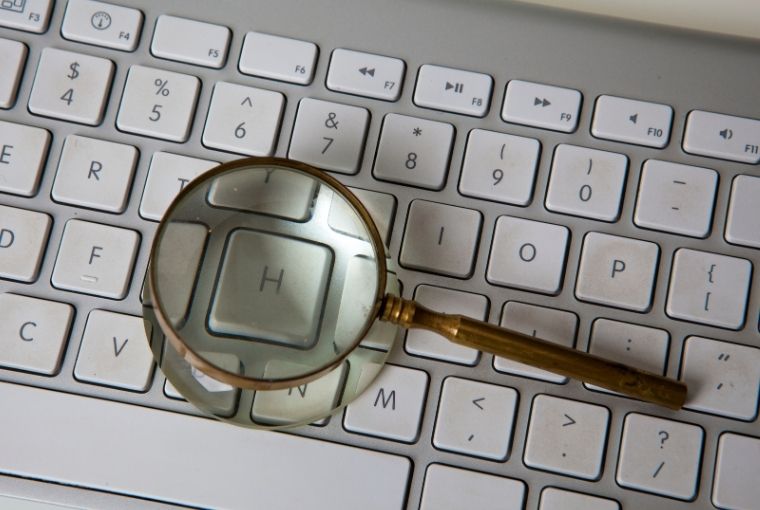 gold magnifying glass on top of keyboard