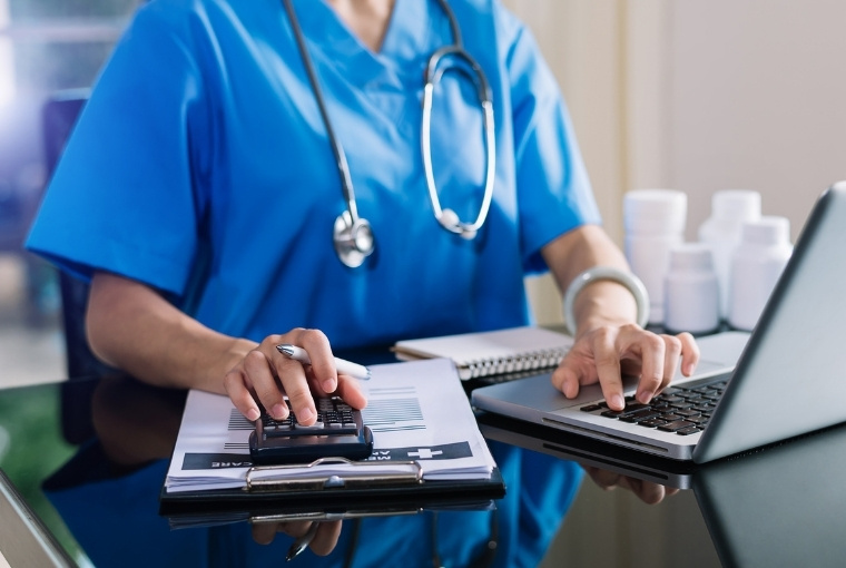 nurse reading data in a laptop while using calculator